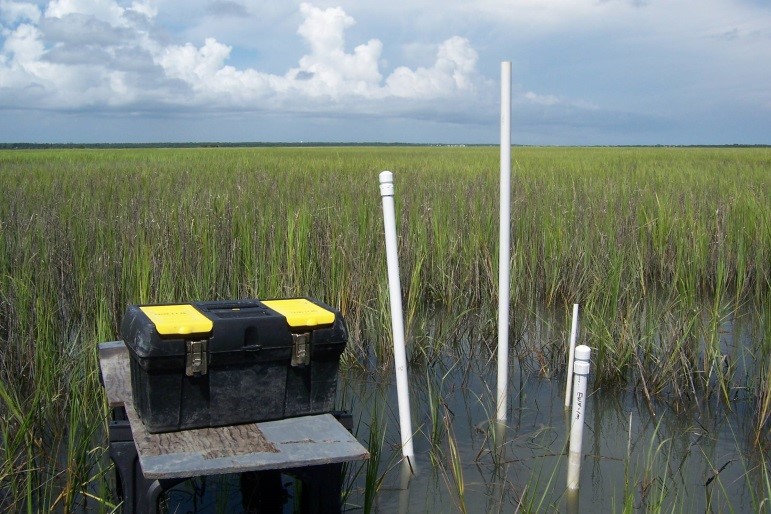 Field equipment and wells on a salt marsh island at high tide